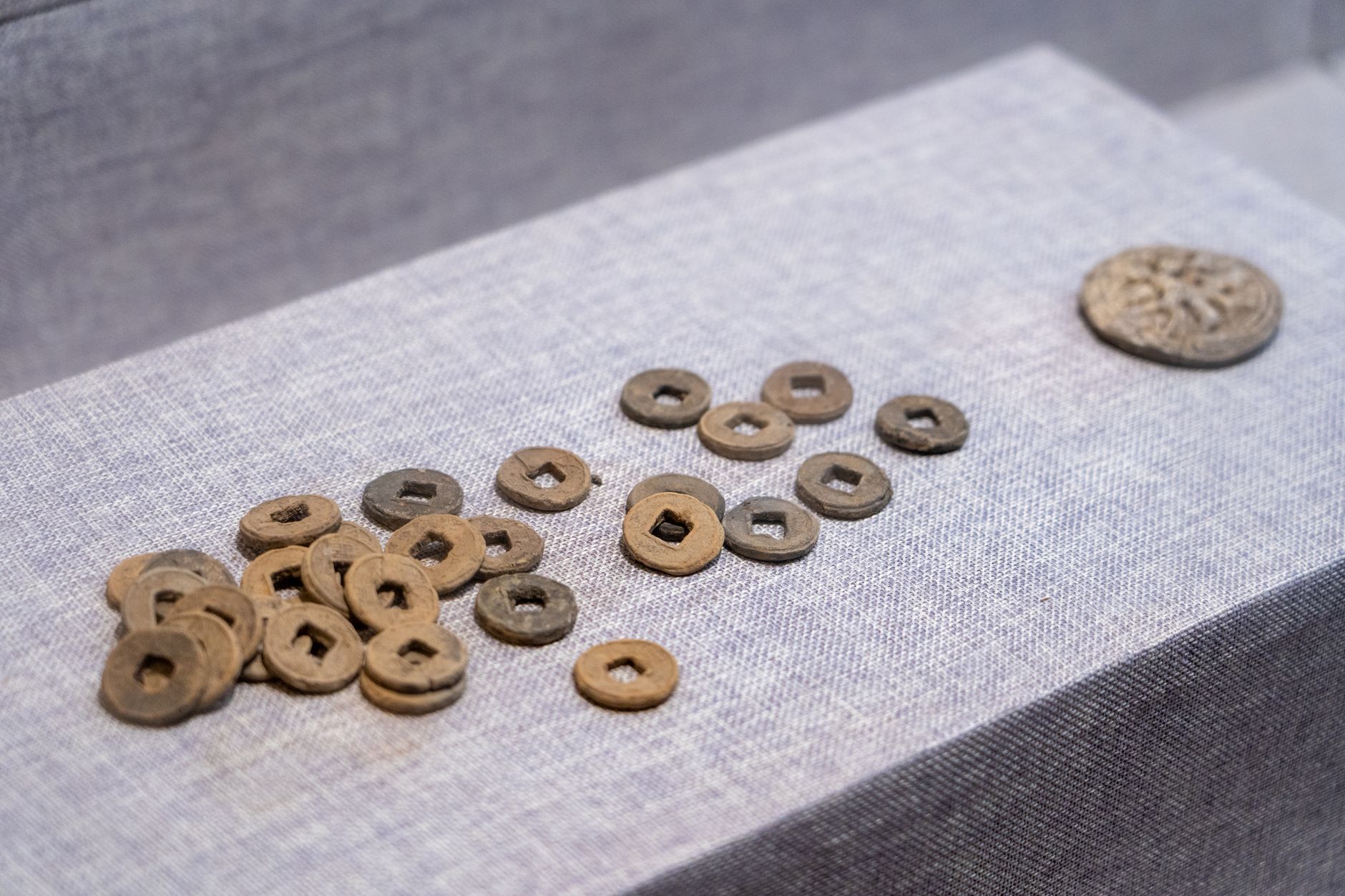 Ancient Chinese coins arranged on a textured fabric platform, showcasing historic currency.