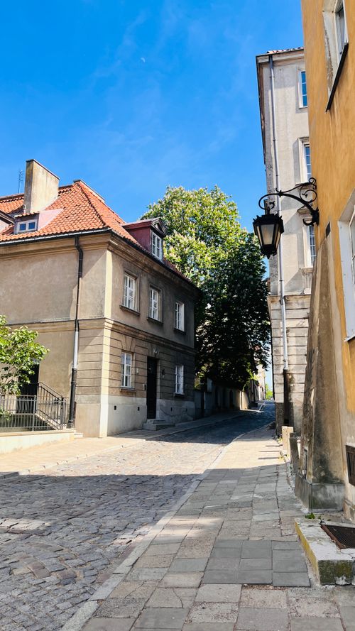 Free A picturesque European street with cobblestones, lined with historic buildings under a clear blue sky. Stock Photo