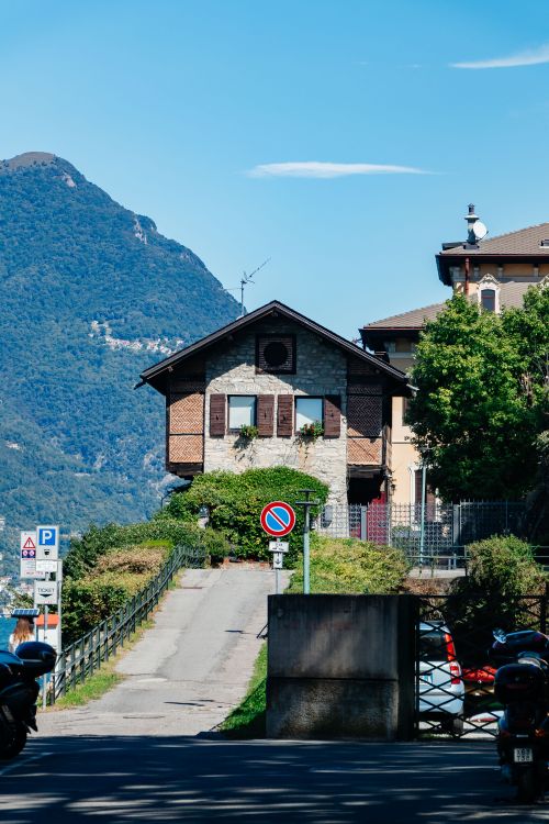 Free Quaint house in Lombardy, Italy, with scenic mountain backdrop on a sunny day. Stock Photo