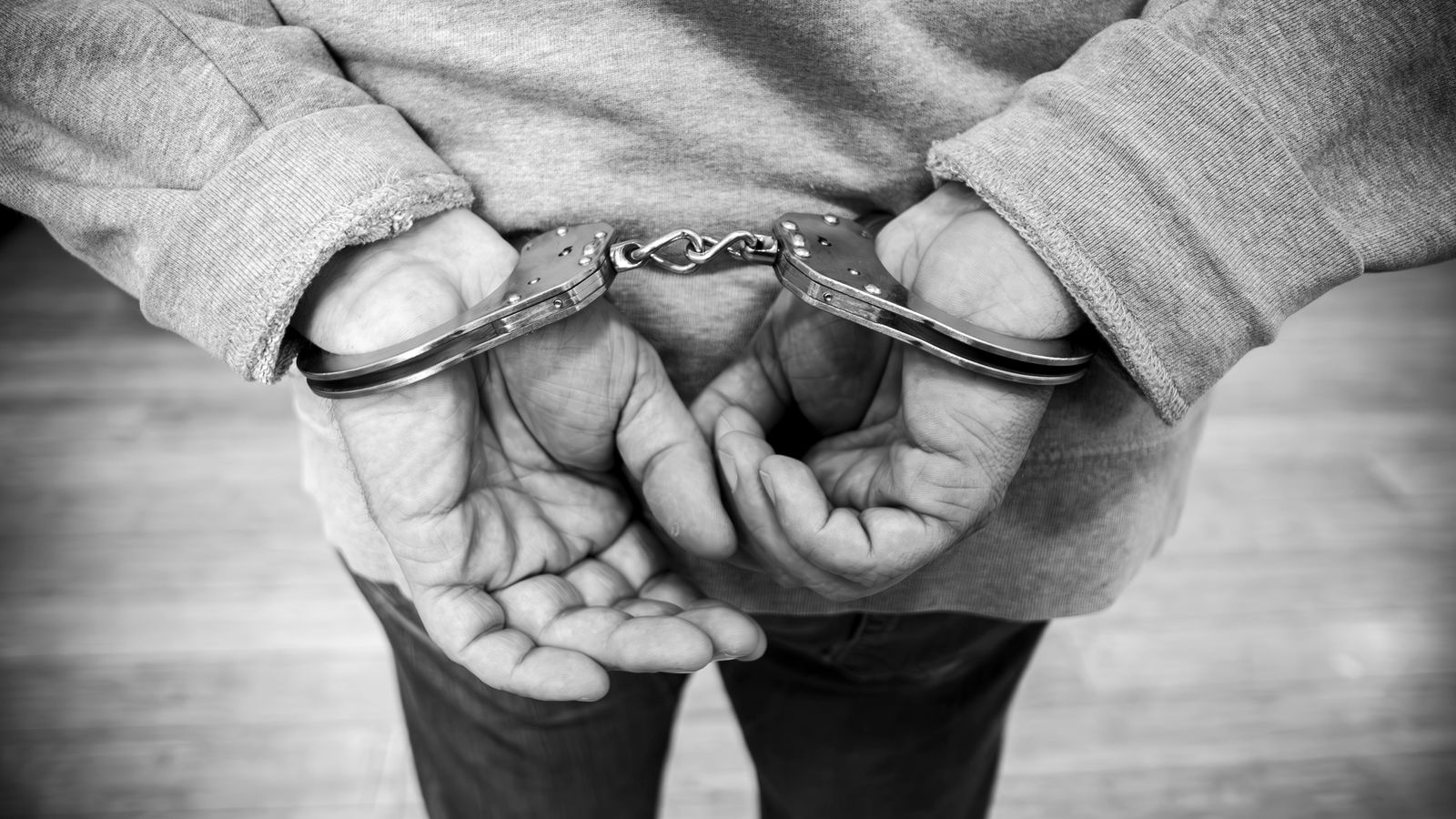 Rear view of a man in handcuffs, captured in monochrome.