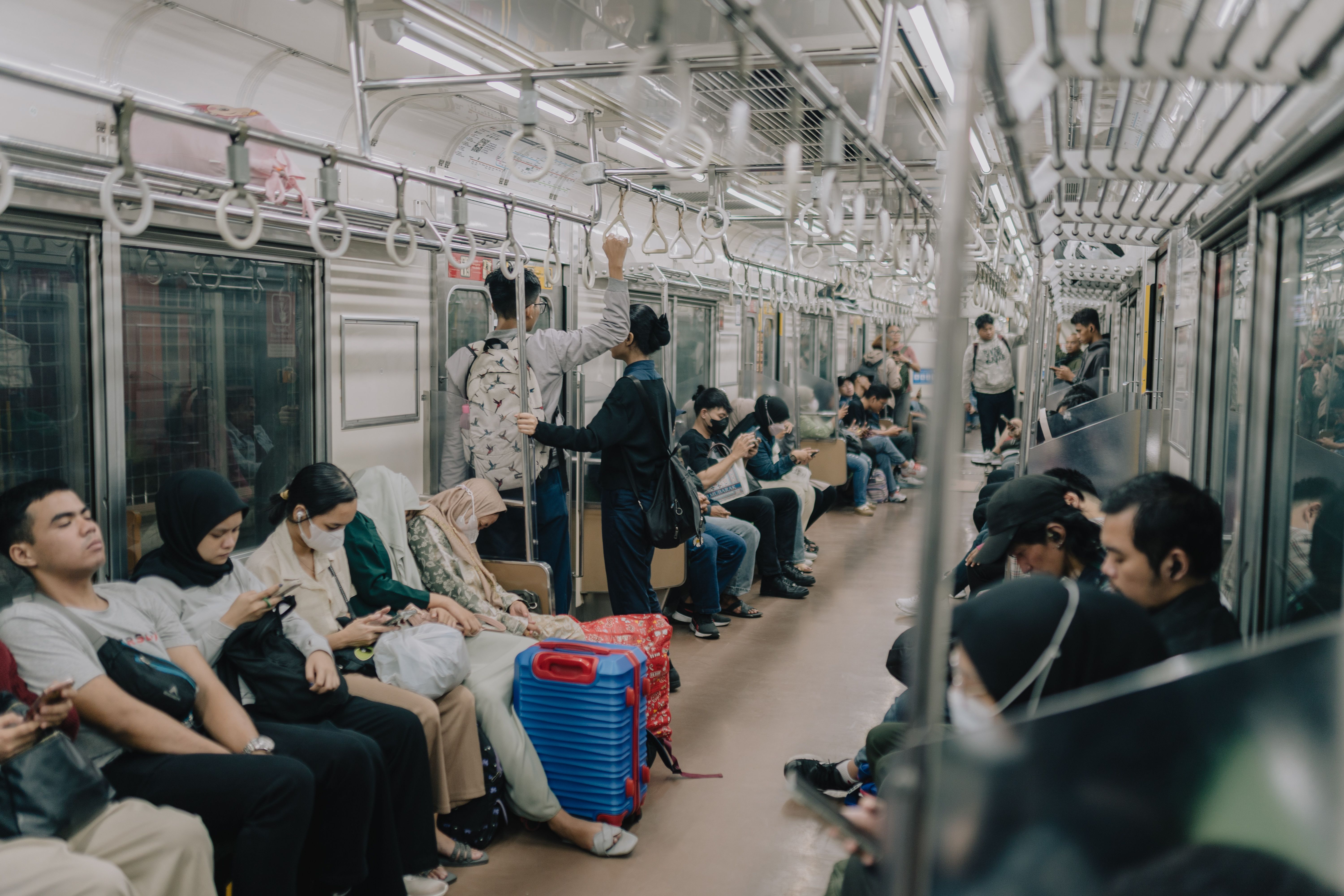 Passengers inside a busy Jakarta subway train during the day, showcasing urban life and daily commute.