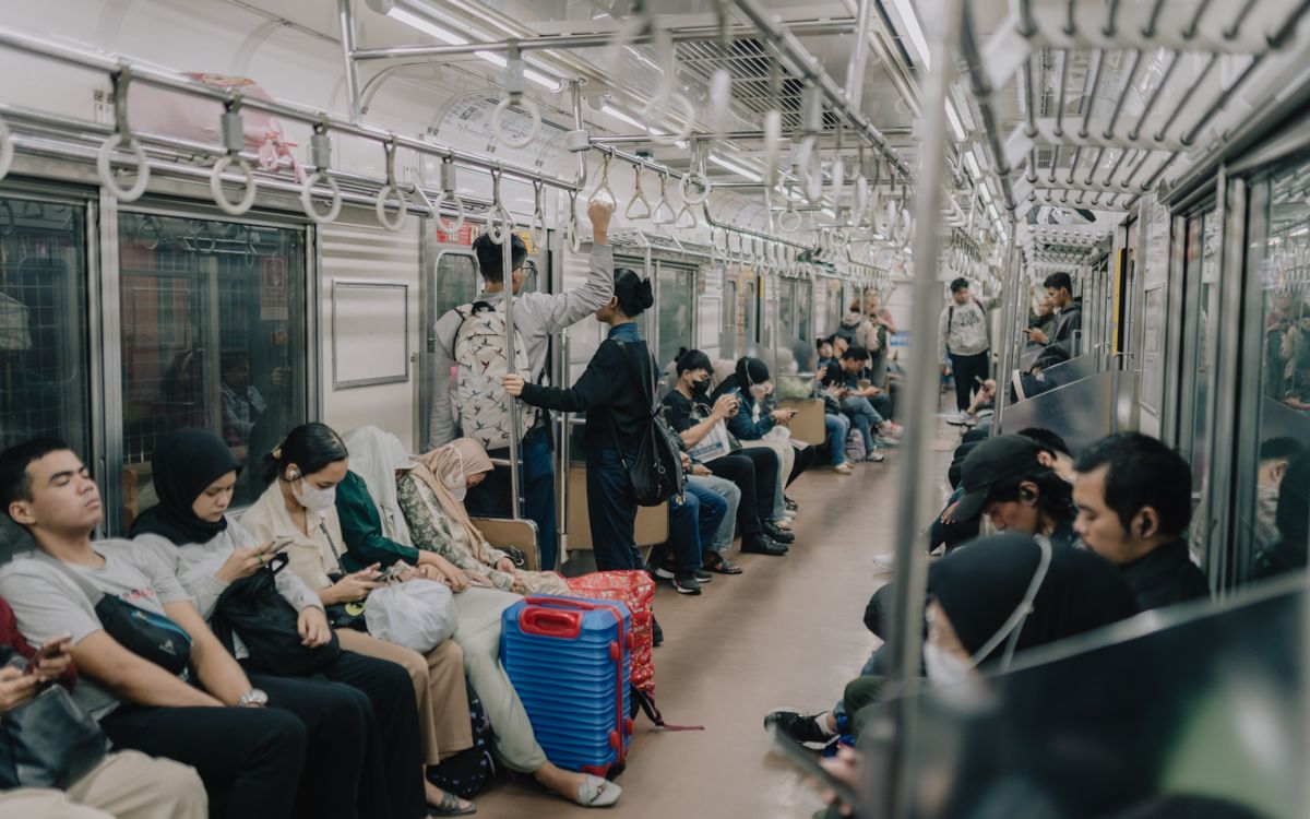 Passengers inside a busy Jakarta subway train during the day, showcasing urban life and daily commute.