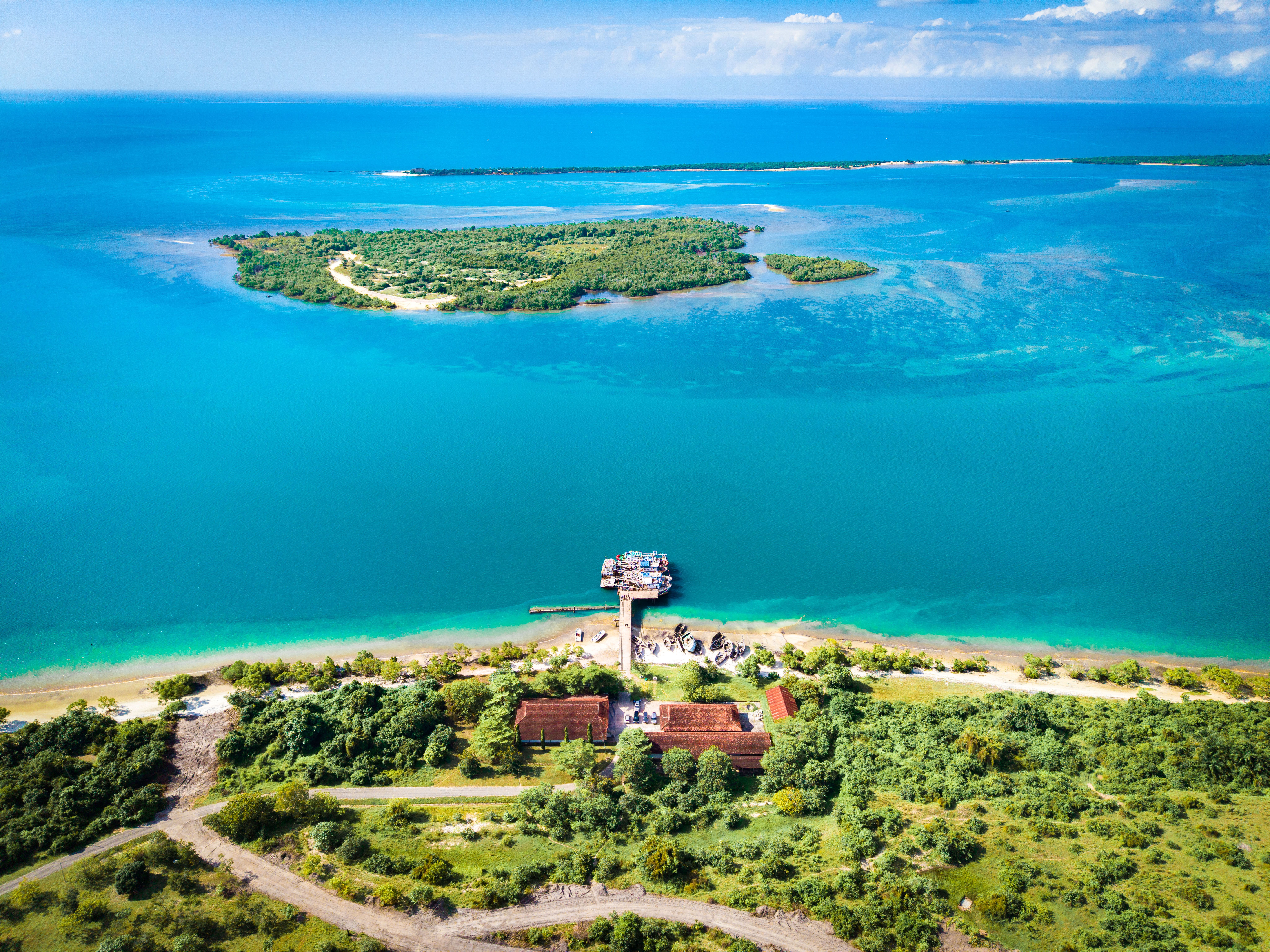 Stunning aerial shot of Bagamoyo's coastline, showcasing vibrant blue waters and lush greenery.
