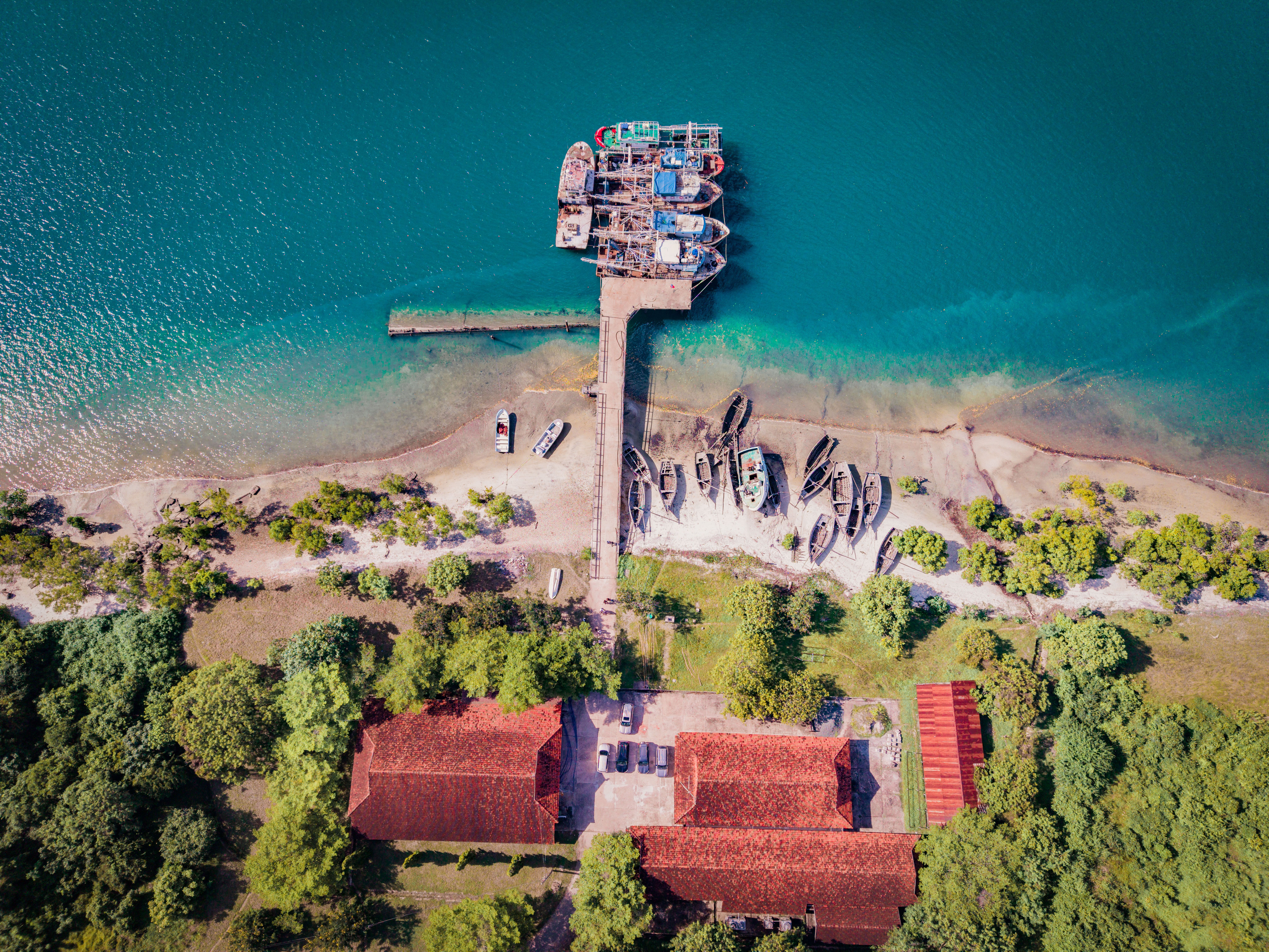 Aerial shot of a dock with colorful boats in Bagamoyo, Tanzania, surrounded by lush greenery.