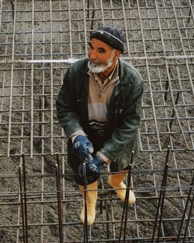 Experienced construction worker stands on a rebar grid at a building site.