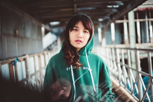 Woman in Green Hoodie Sweater Standing Near White  Metal Railings