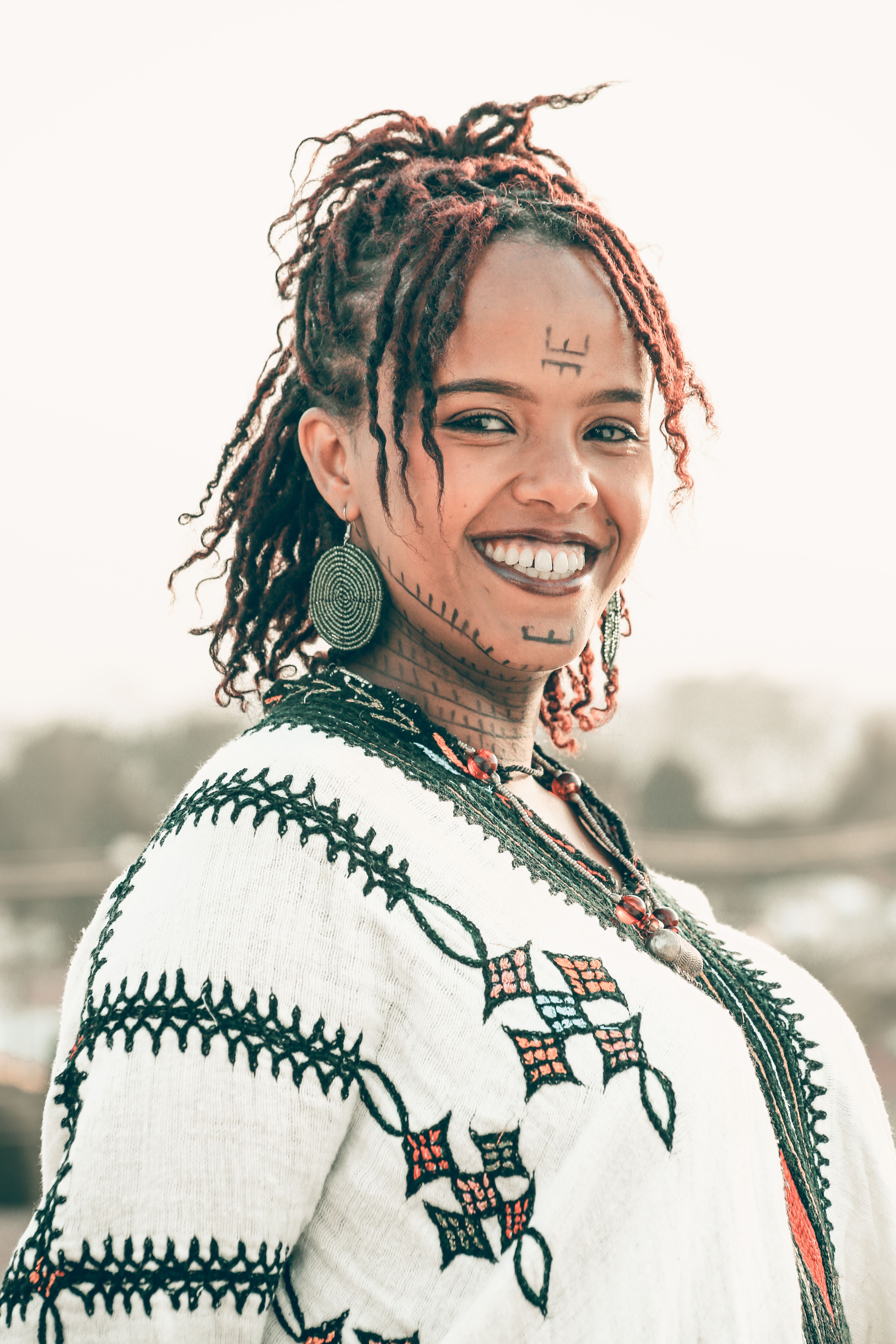 Portrait of a woman in traditional Ethiopian dress with tribal tattoos, showcasing cultural heritage.
