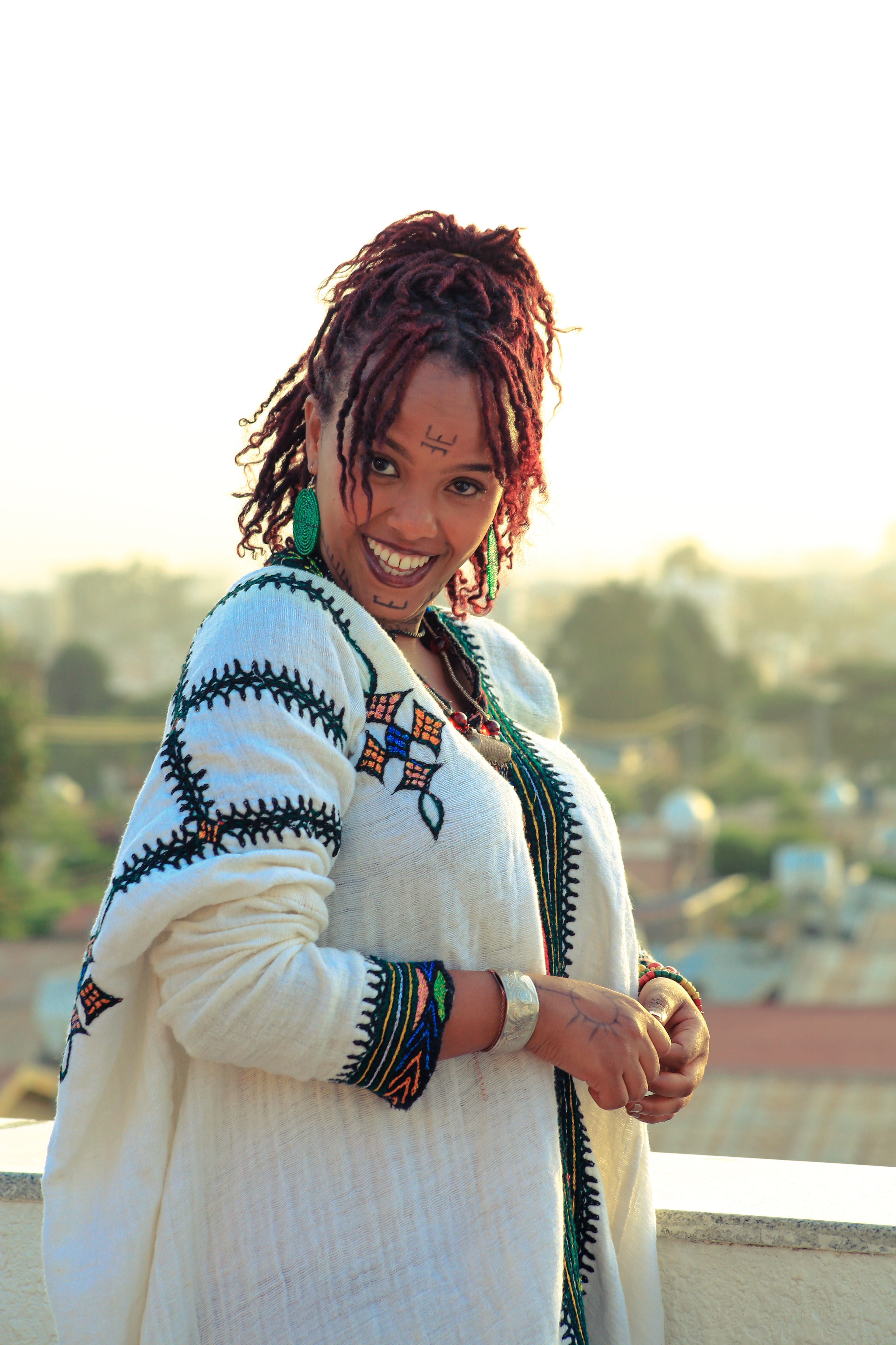 Charming portrait of a woman in traditional Ethiopian dress with a vibrant cityscape backdrop.