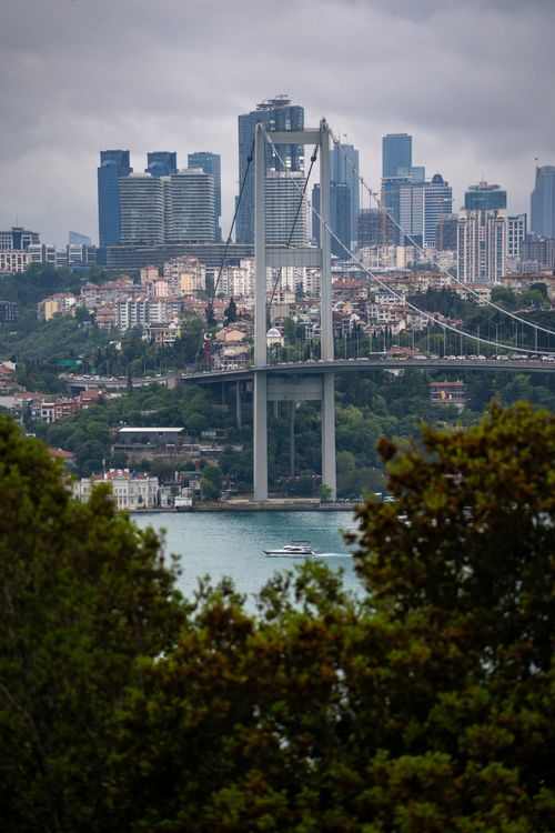 Free View of the Bosphorus Bridge with Istanbul's skyline in the background, featuring modern skyscrapers and a cloudy sky. Stock Photo