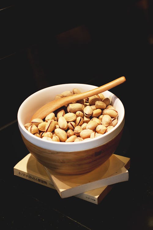 Pistachio Nuts in White and Brown Ceramic Bowl With Brown Wooden Spoon