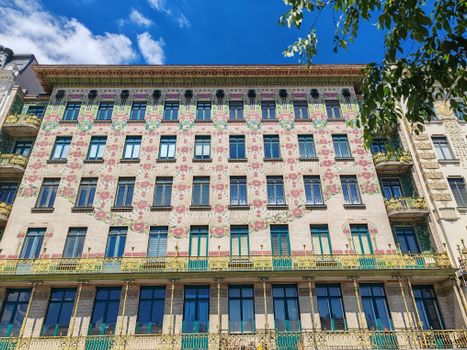 Facade of an Art Nouveau building in Vienna, showcasing intricate floral patterns with vibrant colors under a clear blue sky.