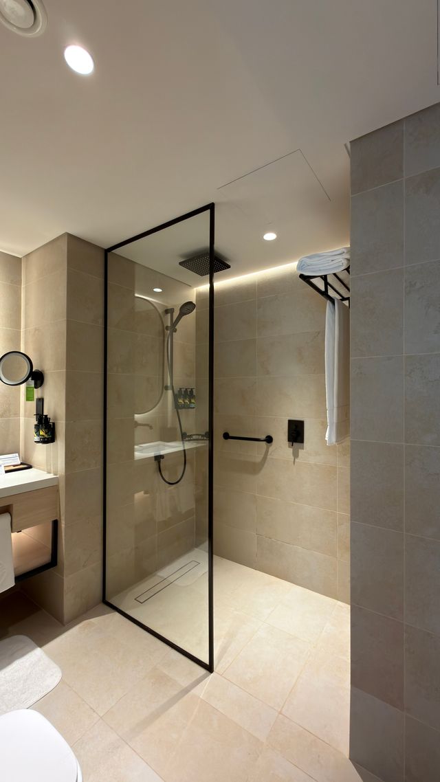 Badezimmer mit beigen Fliesen und Glasdusche