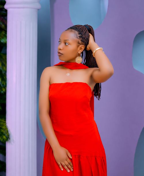 Free Stylish woman in elegant red dress posing indoors with braided hair. Stock Photo