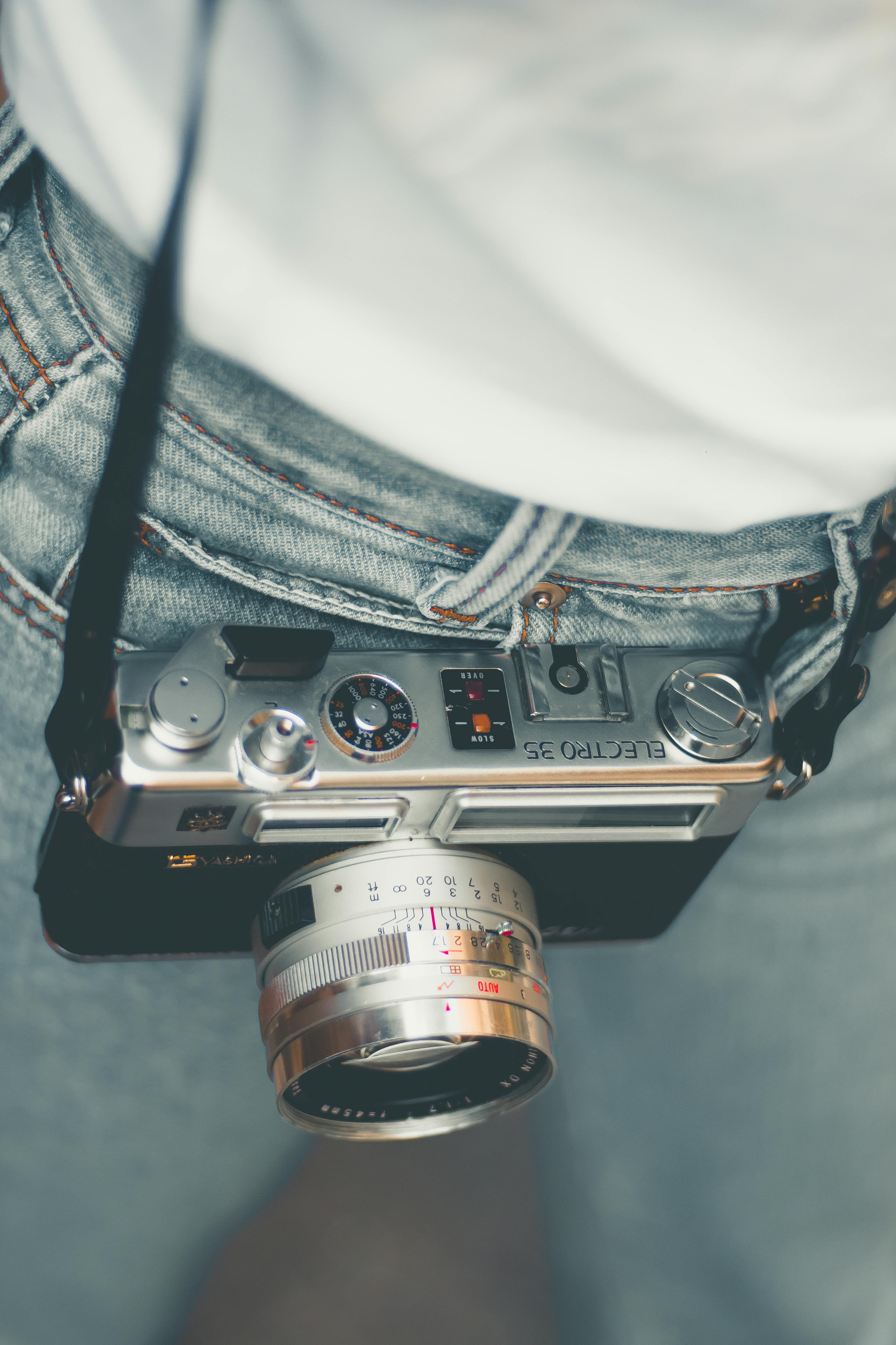 特写镜头展示了一台悬挂在人腰间的老式胶片相机，呈现复古摄影装备