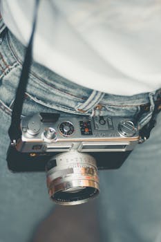 特写镜头展示了一台悬挂在人腰间的老式胶片相机，呈现复古摄影装备