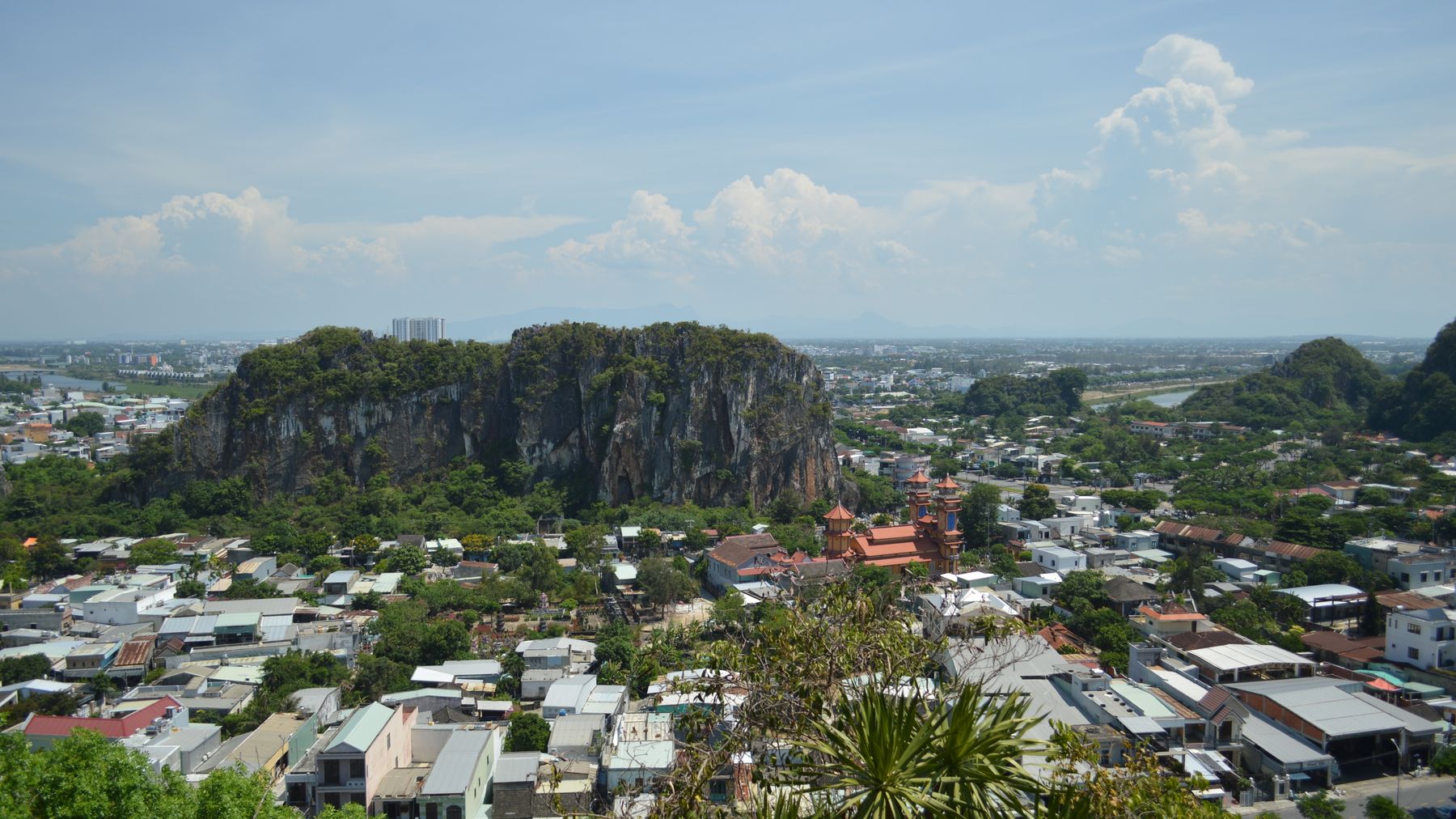 A picturesque aerial view showcasing a city with a prominent rocky hill and lush landscape under a clear blue sky.