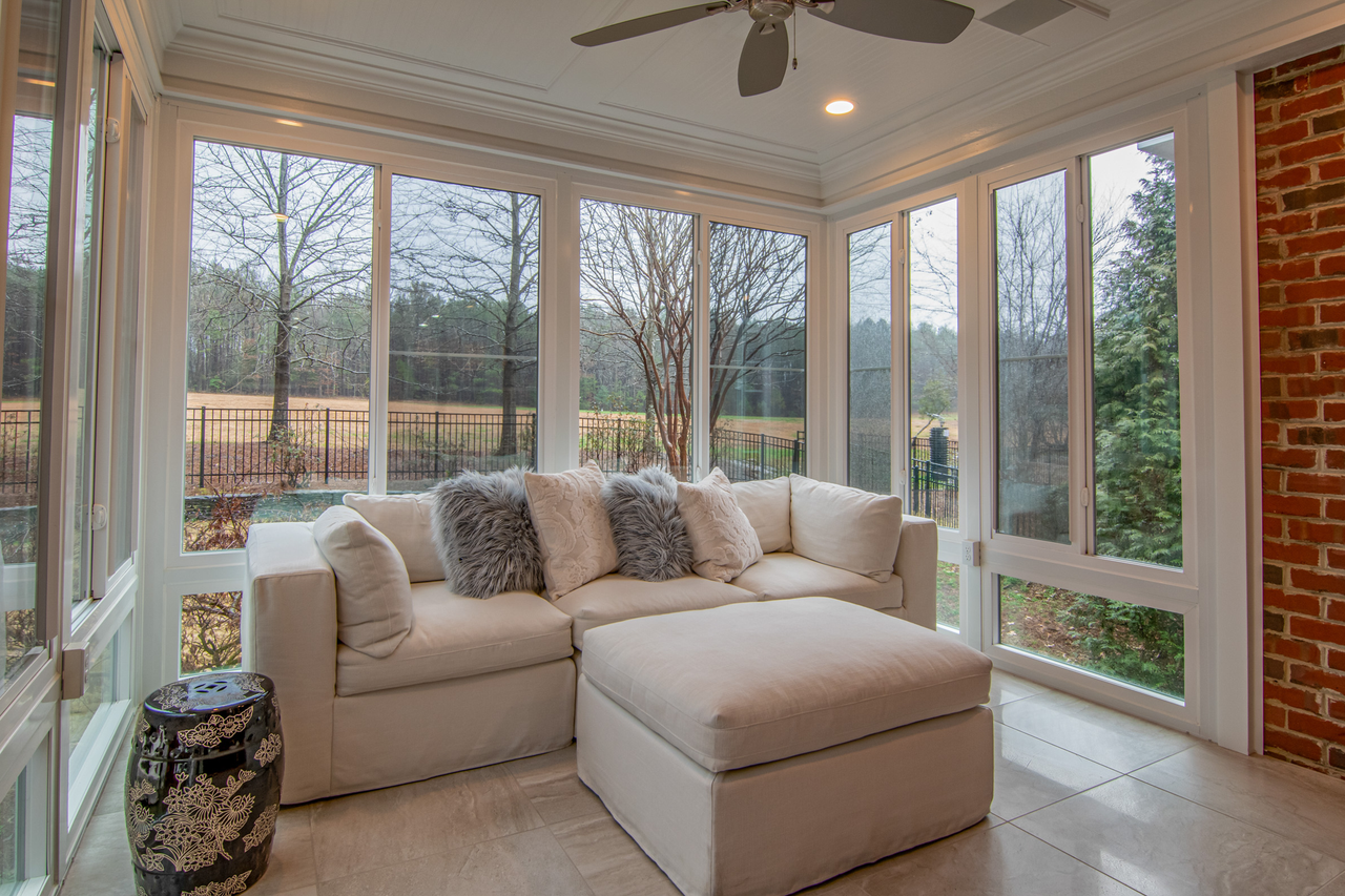 Cosy sunroom with a white sectional sofa and floor-to-ceiling windows
