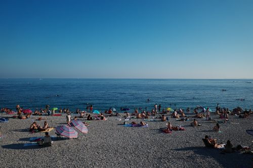 Free A lively beach scene in Nice, France with sunbathers and umbrellas on a sunny summer day. Stock Photo