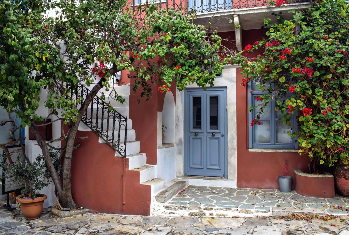Casa rosie cu usa albastra, scara exterioara si bougainvillea