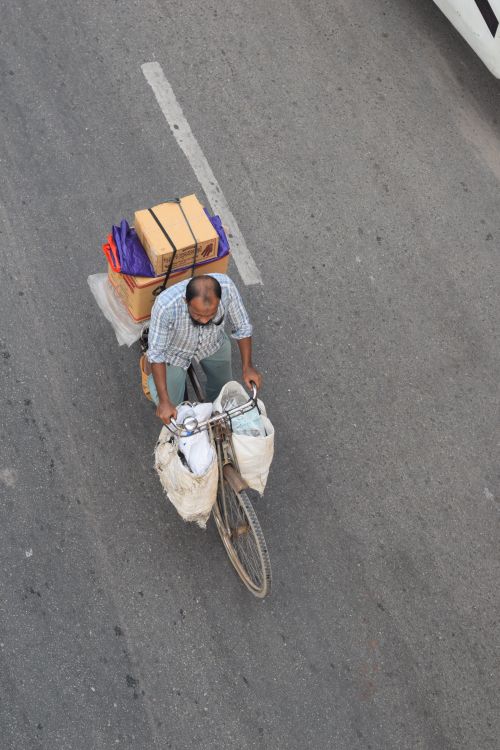 Free Aerial view of a man cycling with packages on a busy street in Dhaka, Bangladesh. Stock Photo