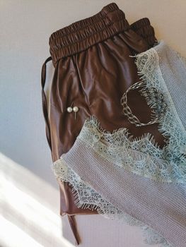 Stylish brown leather pouch with lace fabric and elegant jewelry.