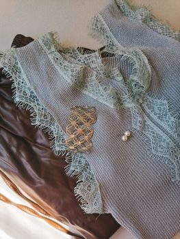 A delicate lace top adorned with a pearl brooch, elegantly placed on contrasting fabric for a stylish look.