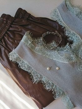 Stylish outfit featuring lace detailed top, brown leather pants, and elegant accessories.