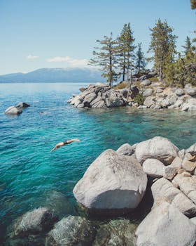 一个人潜入岩石海岸附近水晶般清澈的水中，四周风景如画，环境宁静