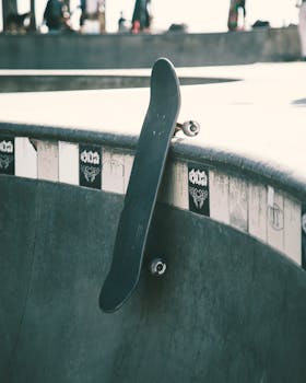 Close-up of a skateboard leaning against a skatepark ramp under daylight.