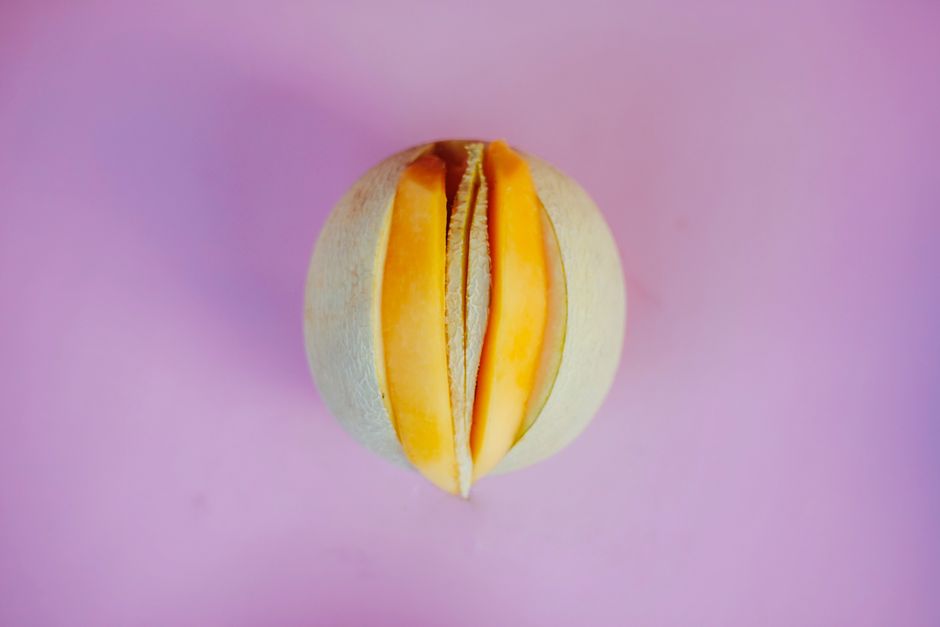 Top view of a sliced melon on a bold pink surface, showcasing contrast and freshness.