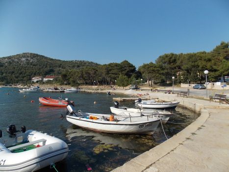 Explore the serene harbor in Drage, Croatia with boats and lush greenery.
