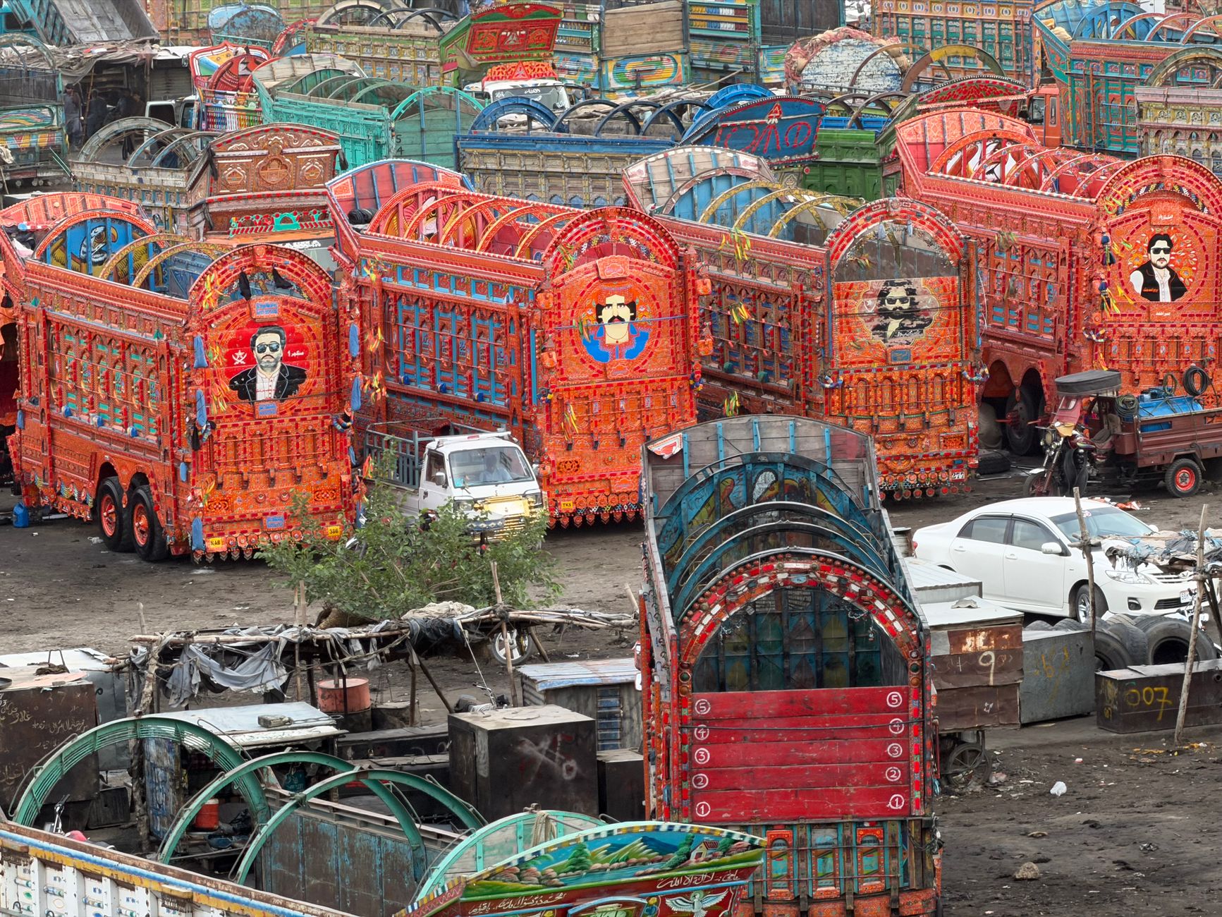 Vibrantly painted trucks showcasing traditional Pakistani truck art parked in a yard.