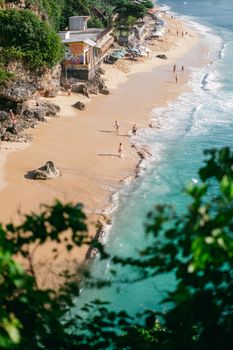 Aerial view of a beautiful tropical beach with clear turquoise waters and people enjoying a sunny day.