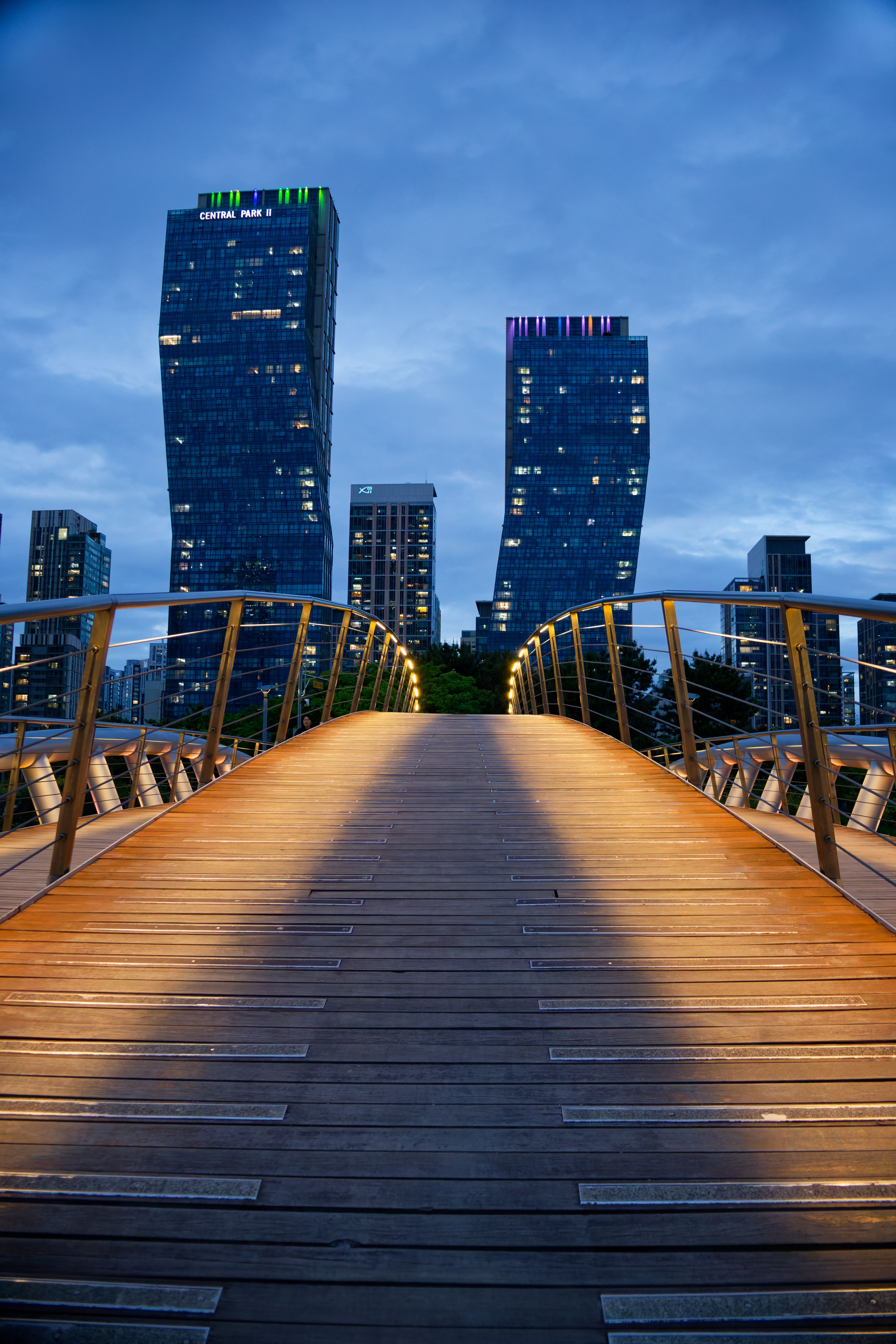 View of illuminated bridge leading to skyscrapers in Incheon, South Korea at twilight.