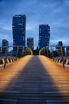 View of illuminated bridge leading to skyscrapers in Incheon, South Korea at twilight.