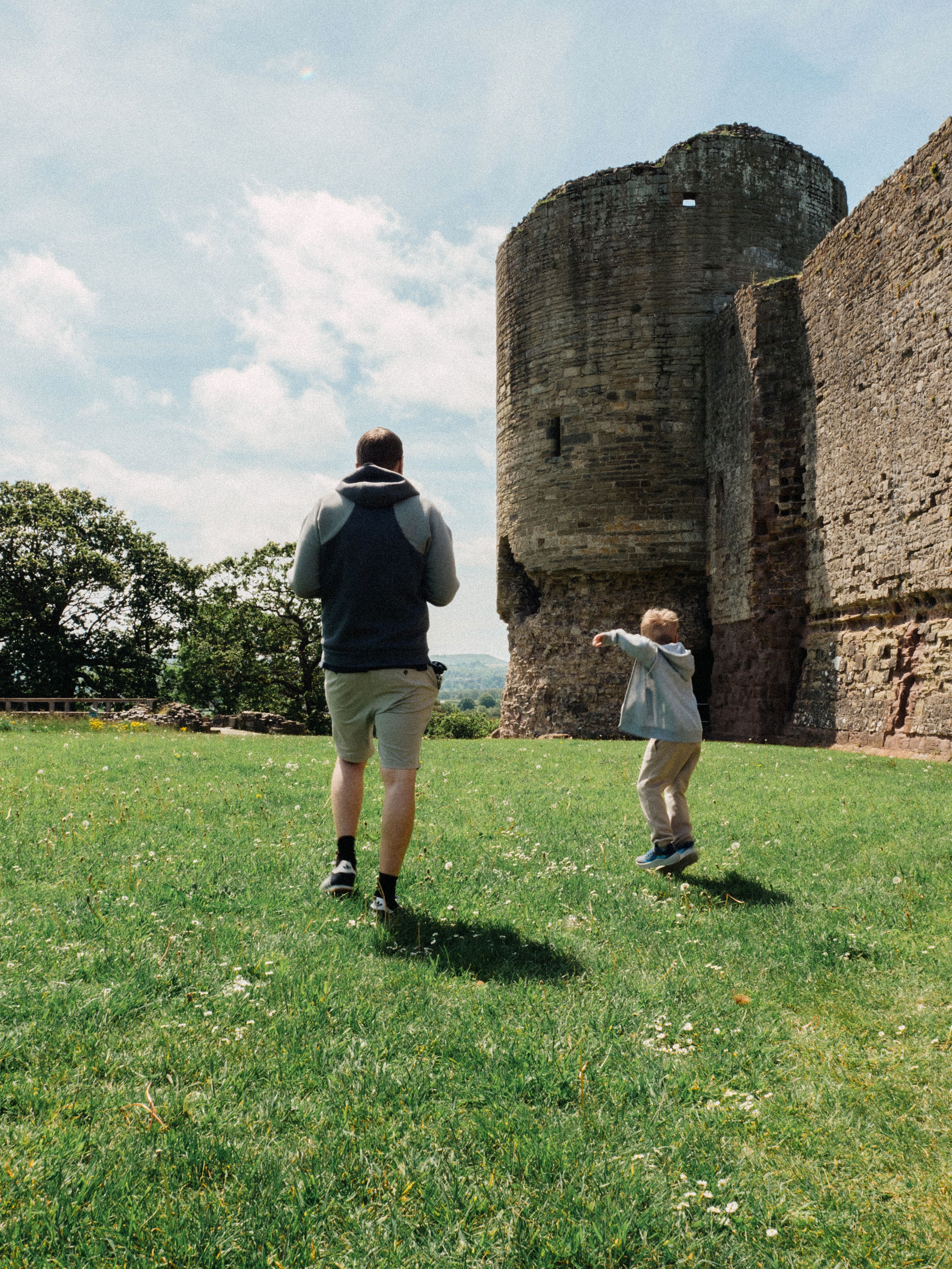 A father and son enjoy a sunny day at Rhuddlan Castle, embracing history.