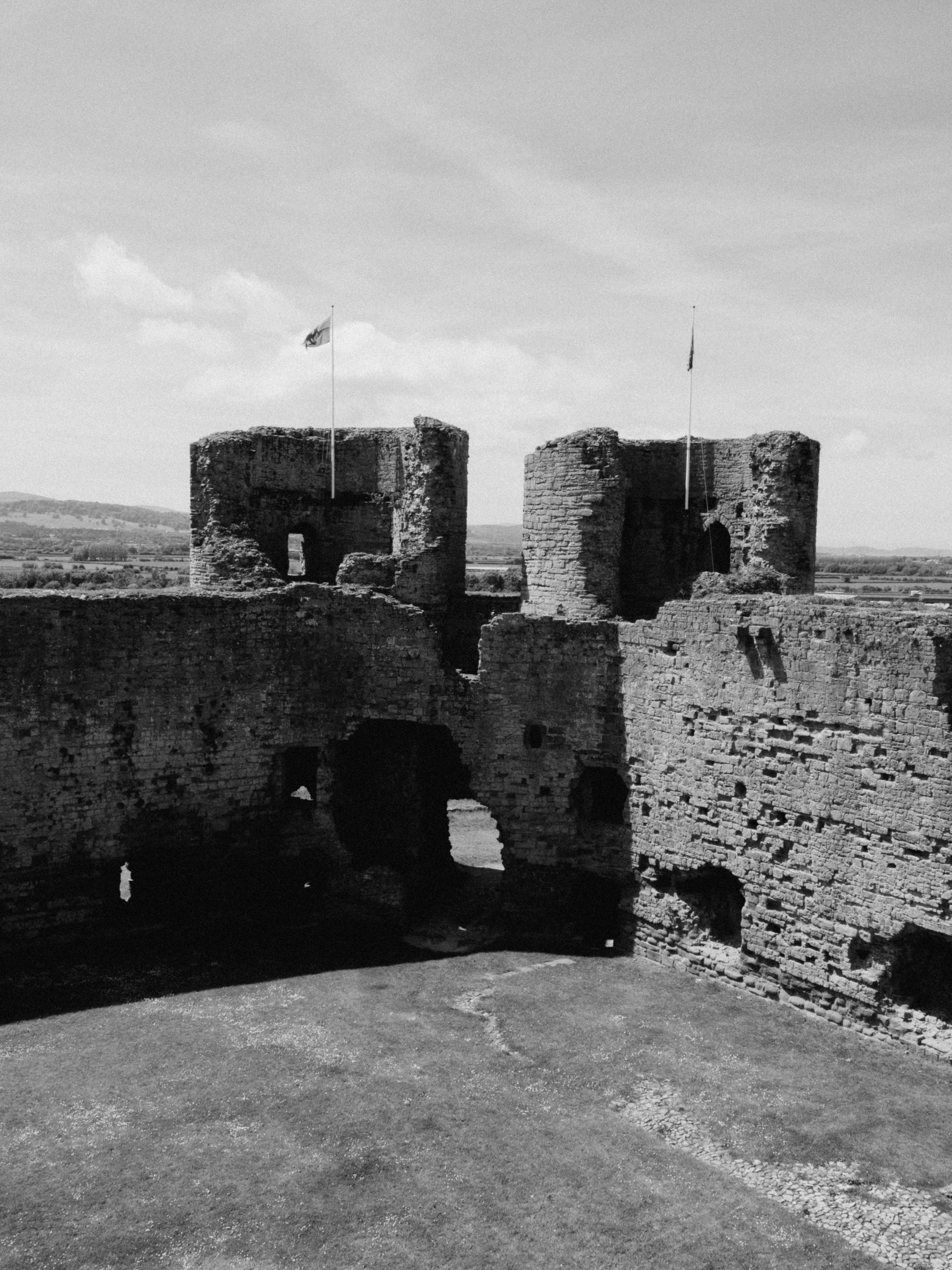 Black and white image of ancient castle ruins under a clear sky.