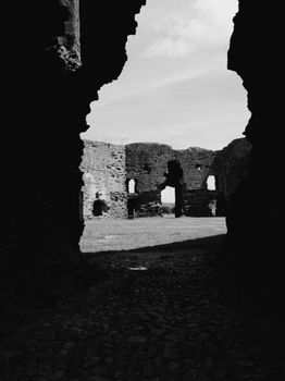 Dramatic black and white view of ancient ruins through a stone archway, capturing timelessness and history.