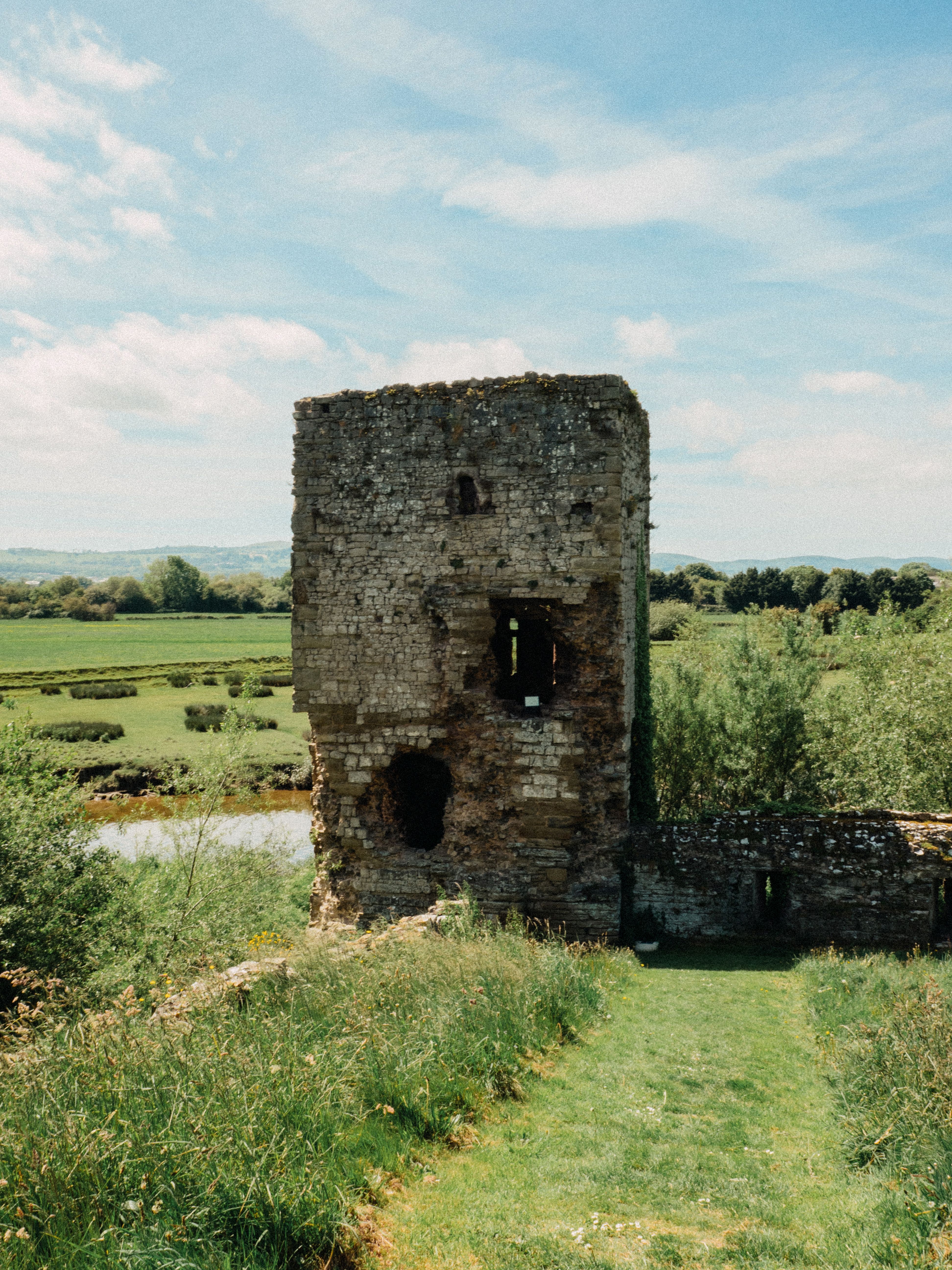 Explore the timeless beauty of ancient ruins set against a lush, green countryside under a bright sky.