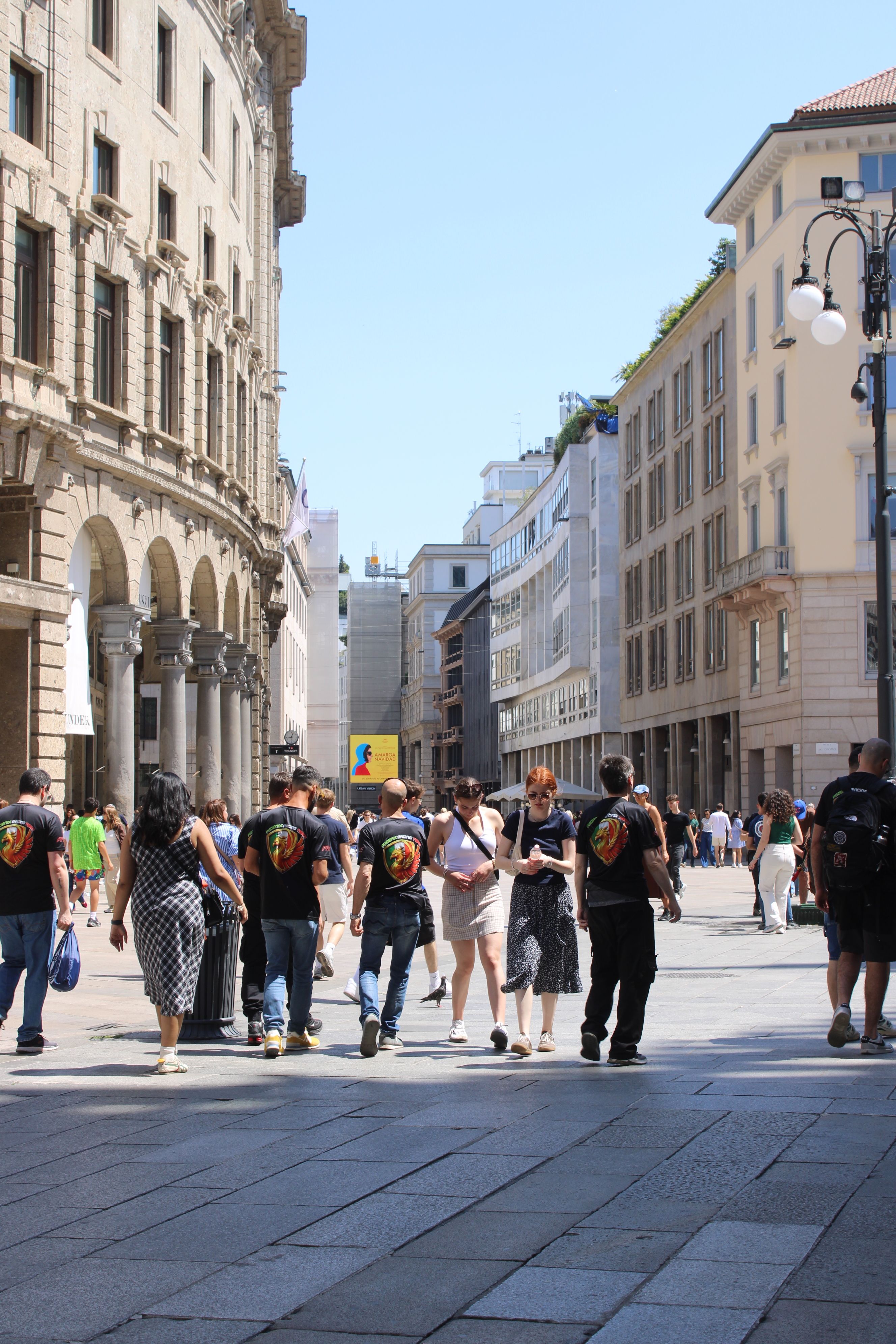 Vibrant street scene in Milan, Italy, featuring locals and tourists on a sunny day.