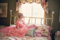 Woman Sitting on Bed Near Window