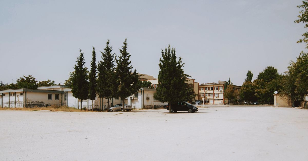 person sitting alone in quiet car parking lot looking at phone