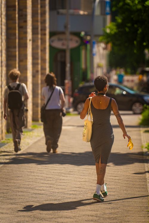 Free People walking on a sunlit sidewalk in a vibrant urban setting Stock Photo