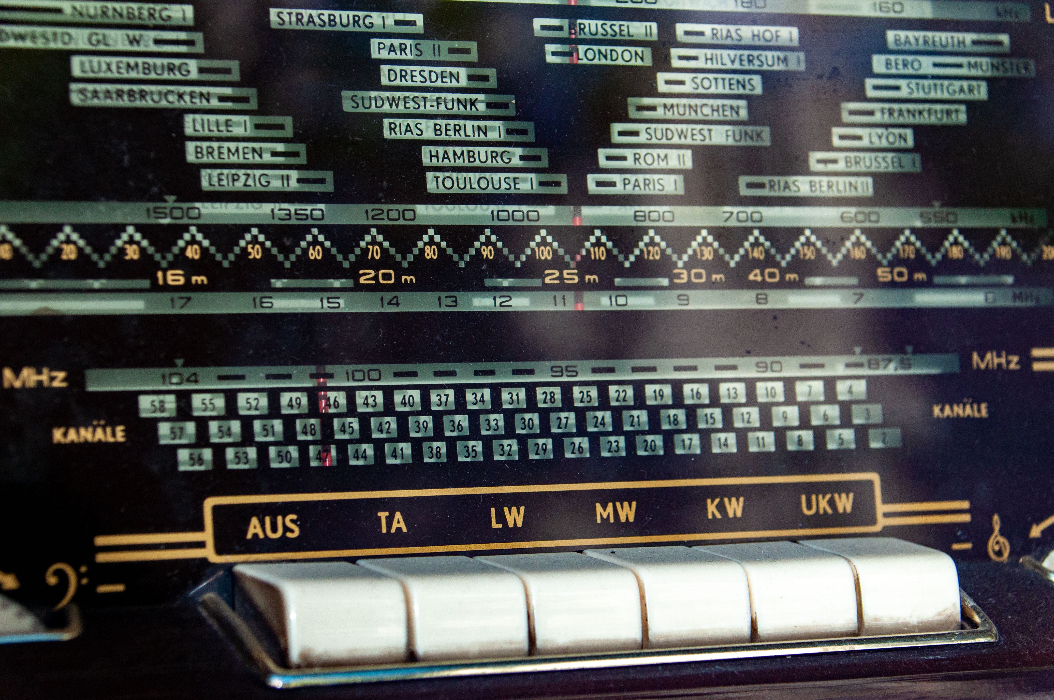 Close-up of a vintage radio dial displaying frequency bands and station names.