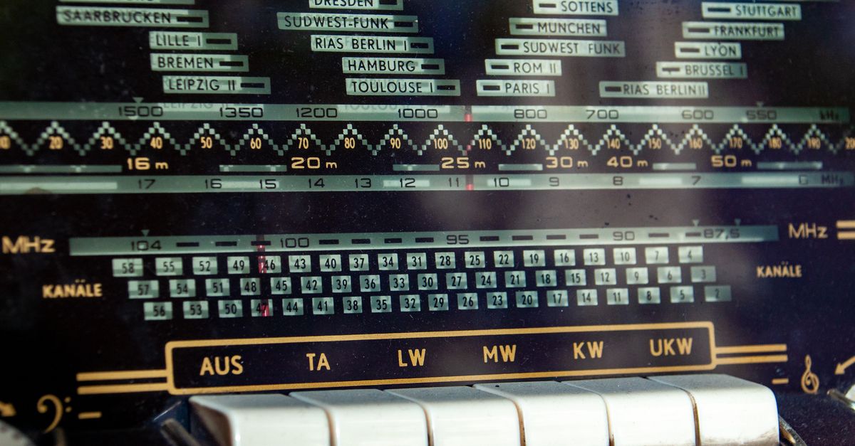 Close-up of a vintage radio dial displaying frequency bands and station names.