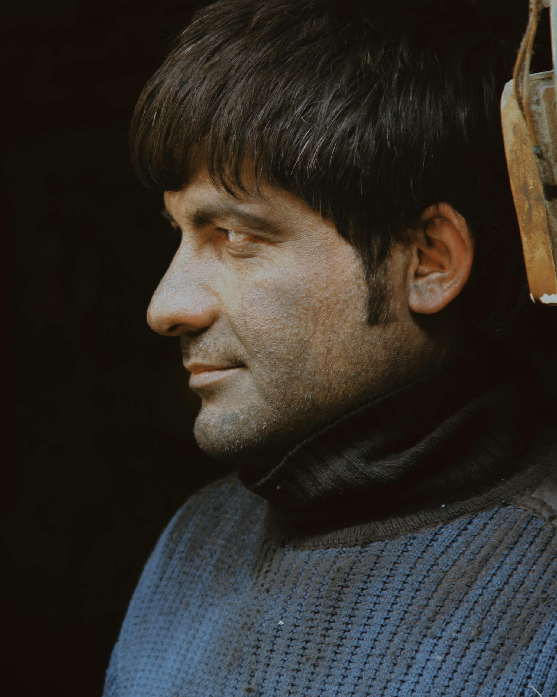 Side profile portrait of a man in warm tones, wearing a blue sweater.