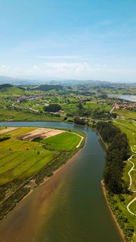 Aerial view of lush green fields and river in Cantabria, Spain.