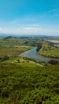 Aerial view of lush green landscape with winding river in Cantabria, Spain.