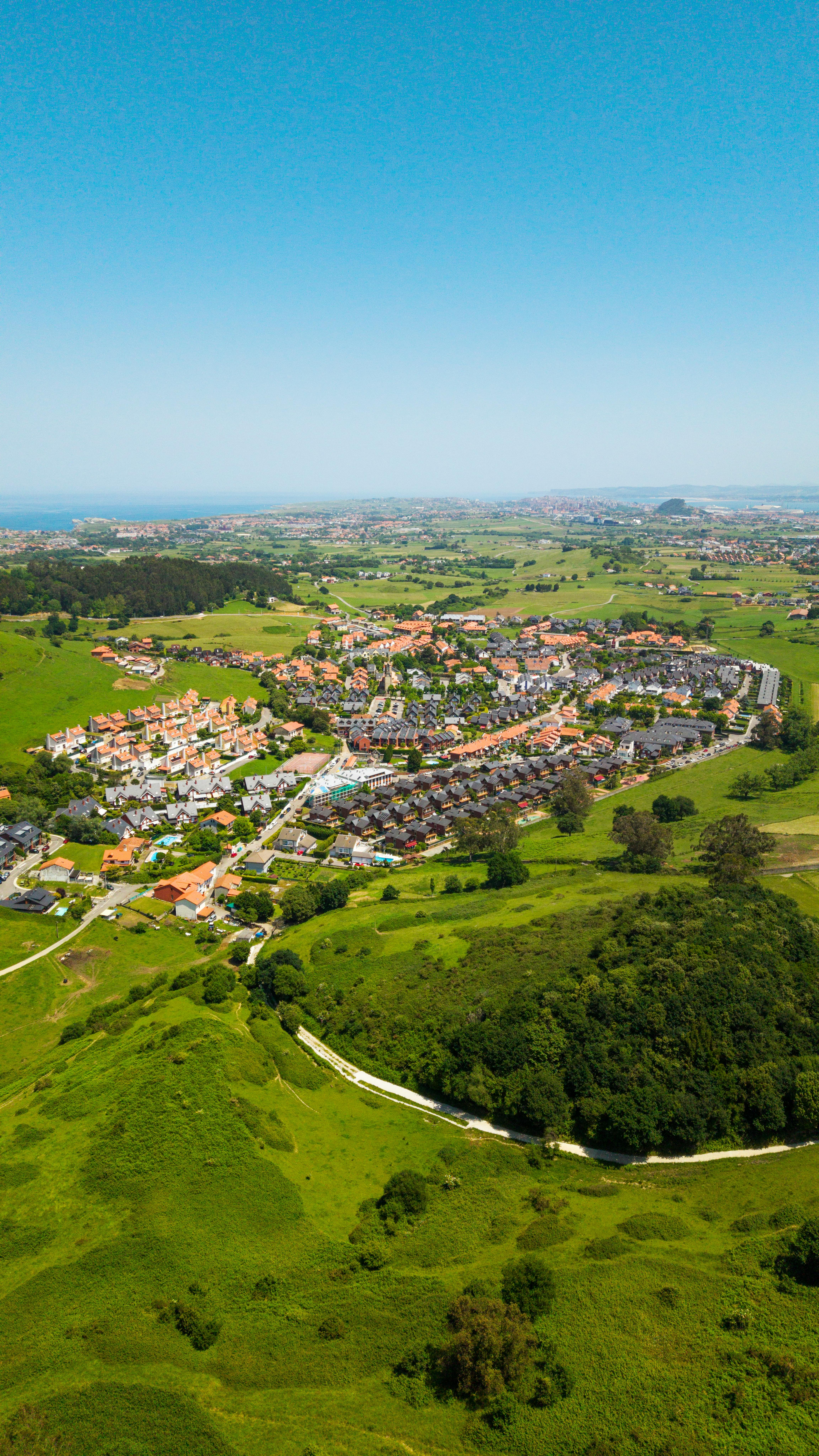 Aerial shot of a picturesque village surrounded by lush greenery near the coast of Spain.