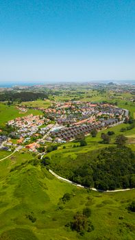 Aerial shot of a picturesque village surrounded by lush greenery near the coast of Spain.